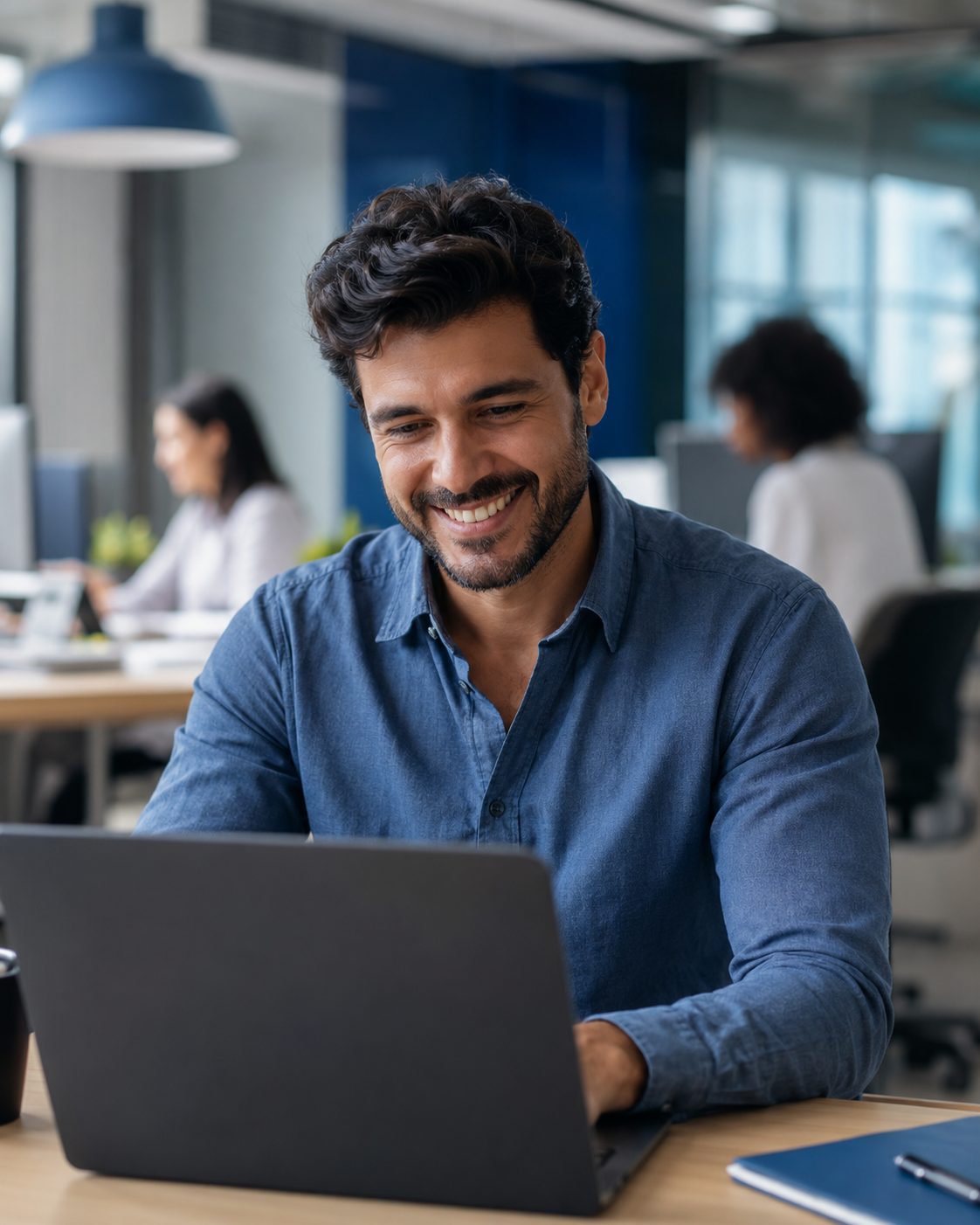 Profissional sorrindo enquanto usa o notebook em um escritório moderno